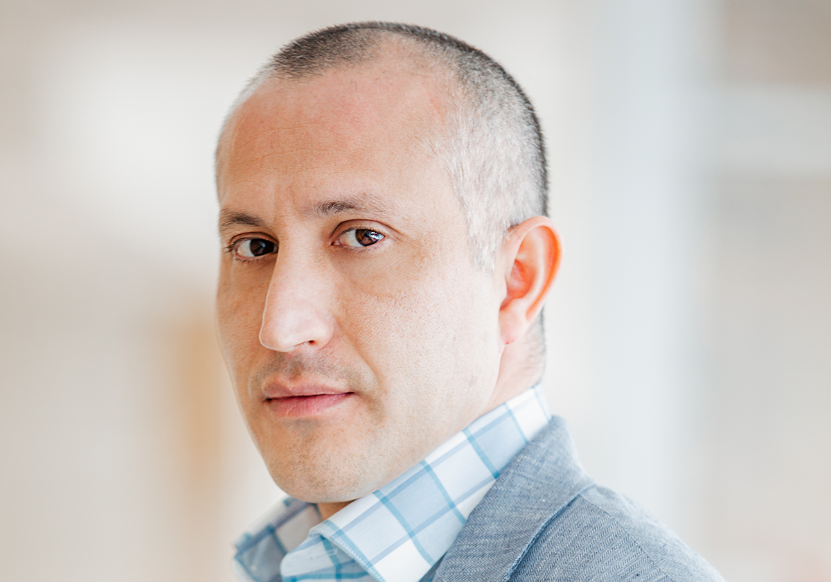 Francisco is a man wearing a blue shirt and grey blazer, looking into the camera.  