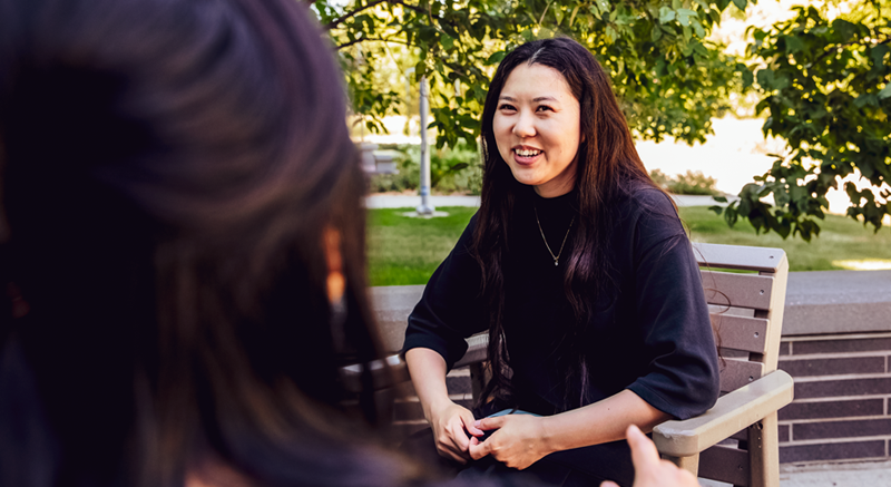 A student dressed in black converses with a counselor.